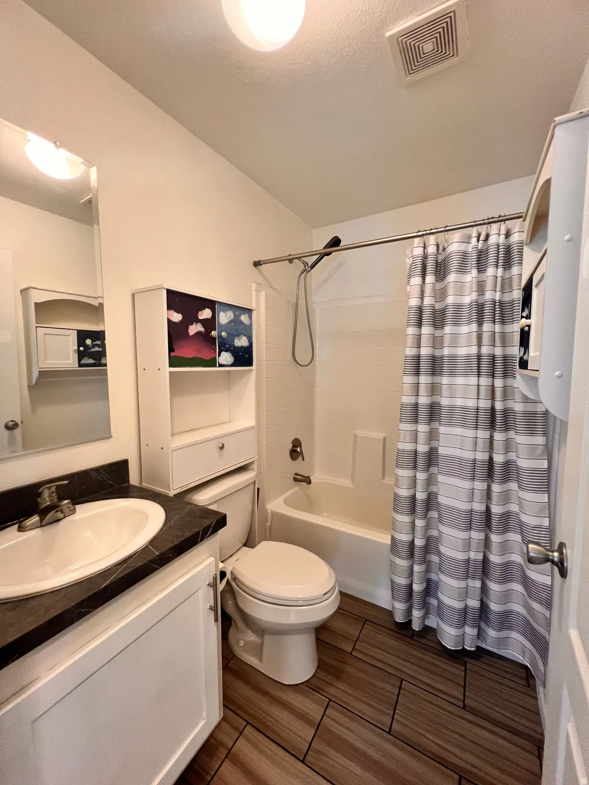 Full bathroom featuring a white vanity with a dark countertop, an undermount sink, and a matching mirror