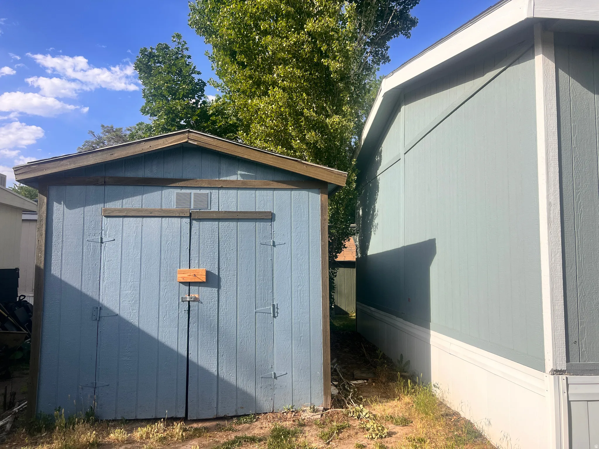 Detached storage shed featuring a dual-door entry, wooden construction, and a pitched roof