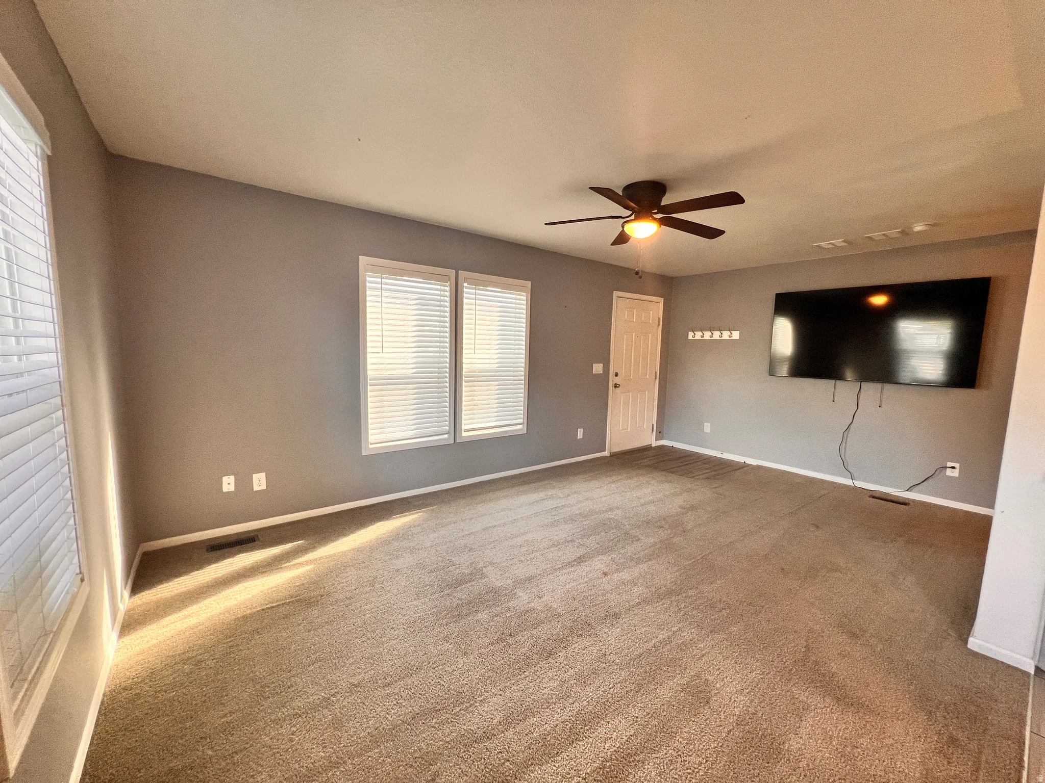 Spacious living area featuring neutral carpeting and light gray wall finishes. 75 inch tv included
