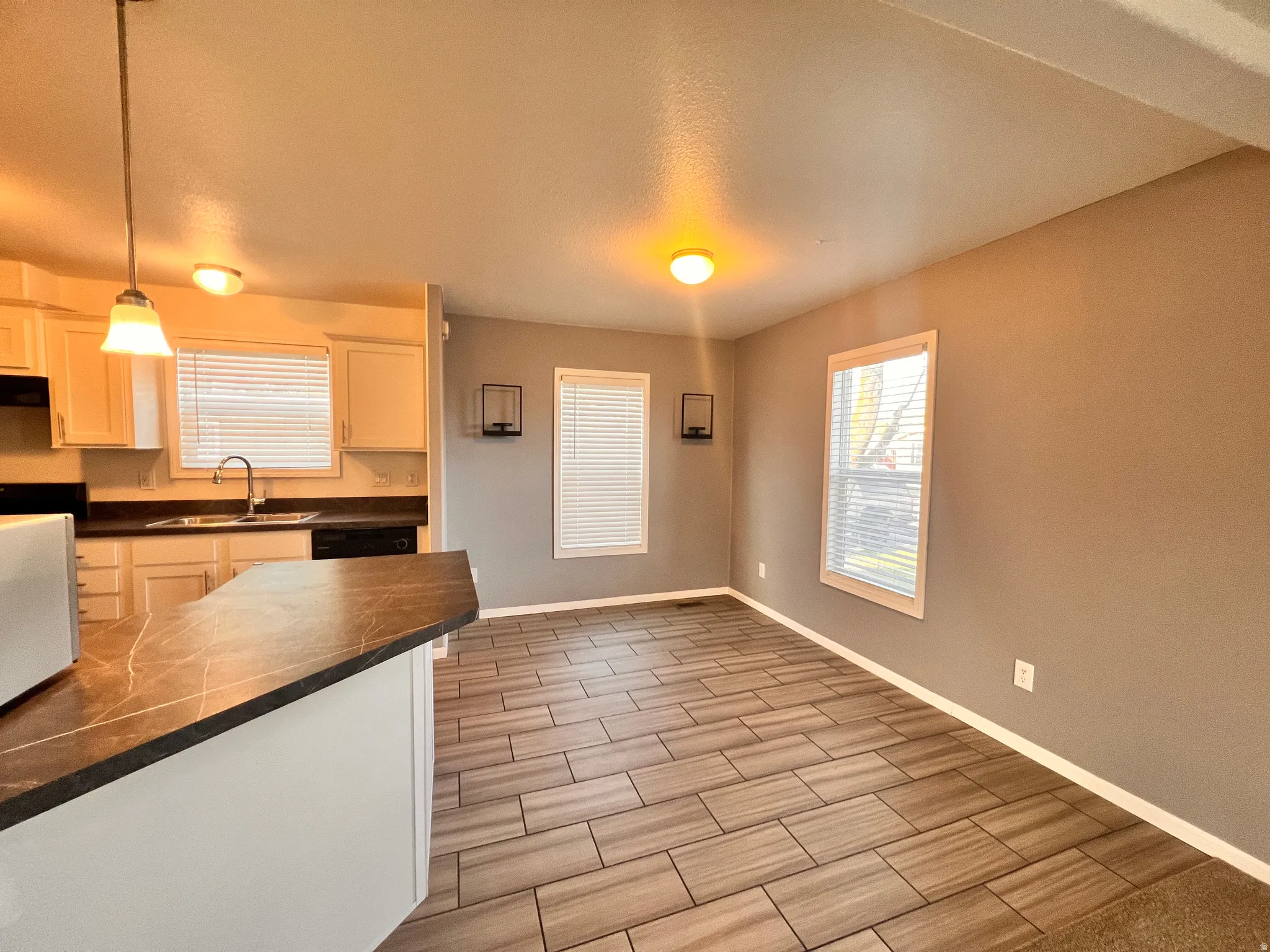 Open-concept kitchen and dining area featuring a breakfast bar with a dark countertop, white cabinetry, and a stainless steel sink