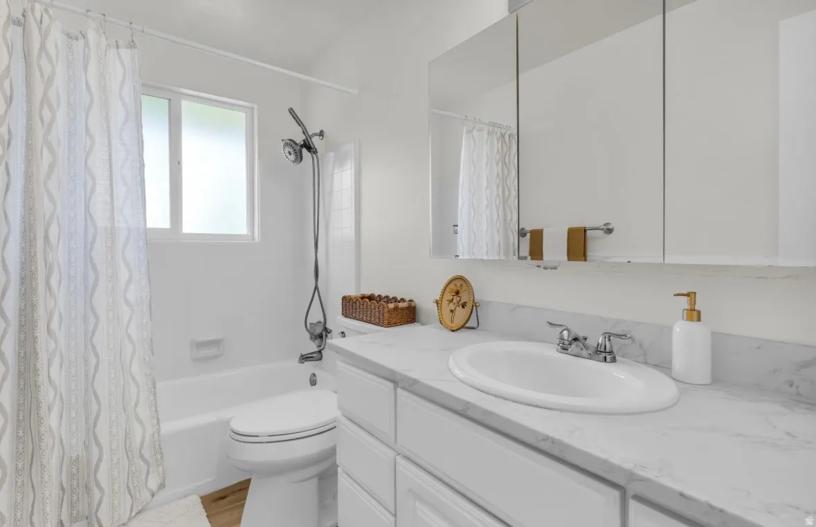 Bathroom featuring a white vanity with an undermount sink, a stone-finish countertop, and a mirrored medicine cabinet