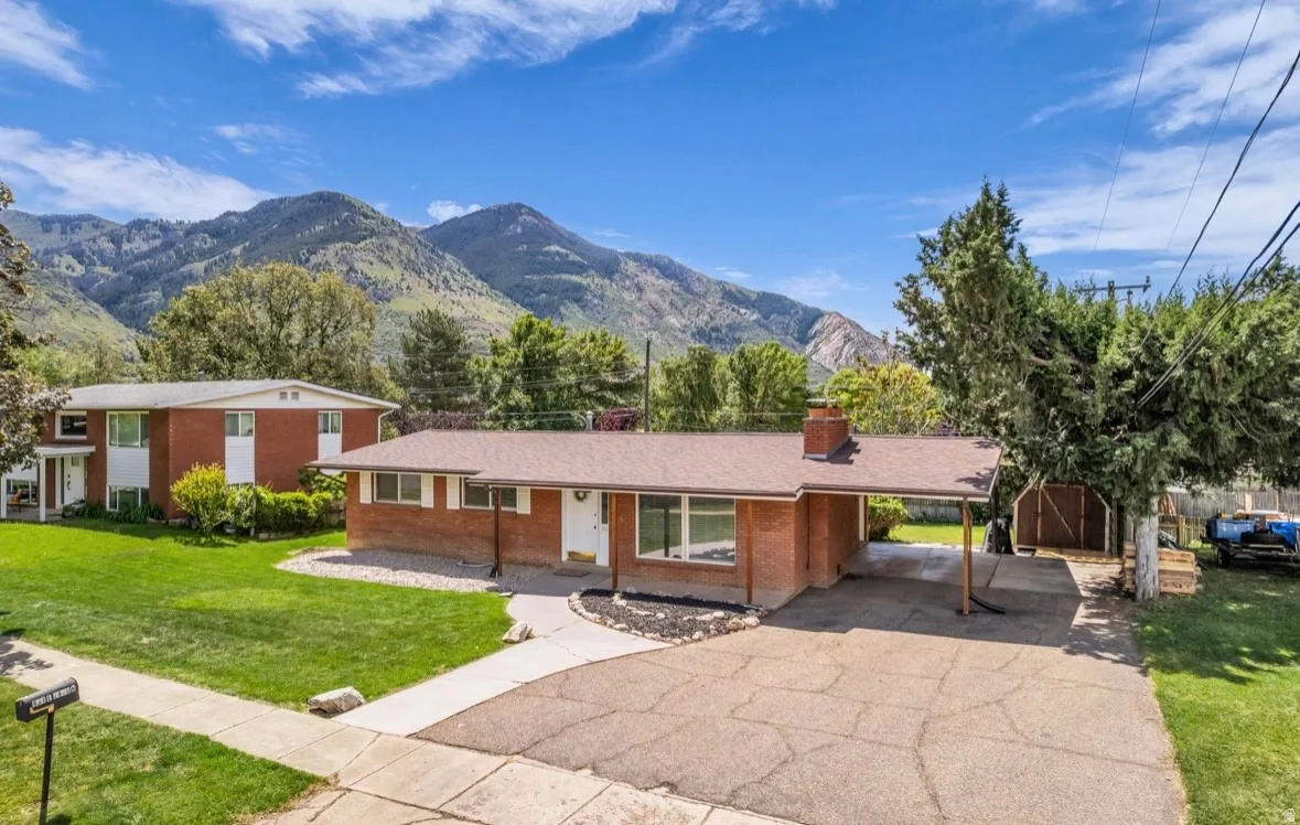 Brick ranch-style home featuring a covered carport, a concrete driveway, and a front walkway