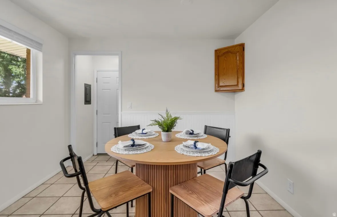 Dining area featuring tile flooring, wainscoting, and a wood-finish wall cabinet