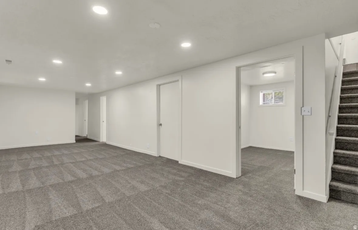 Spacious multi-purpose room featuring patterned carpeting, recessed lighting, and white trim throughout