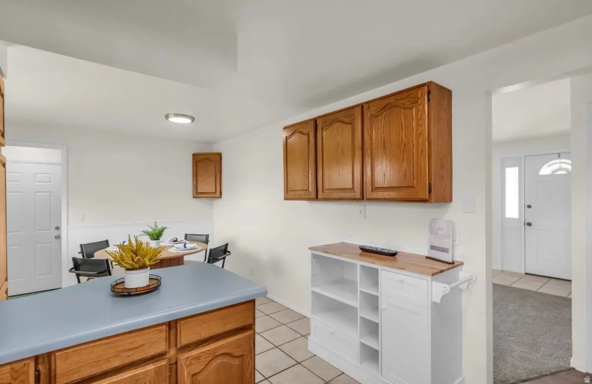 Kitchen featuring wood-finish cabinetry, light countertops, and square tile flooring