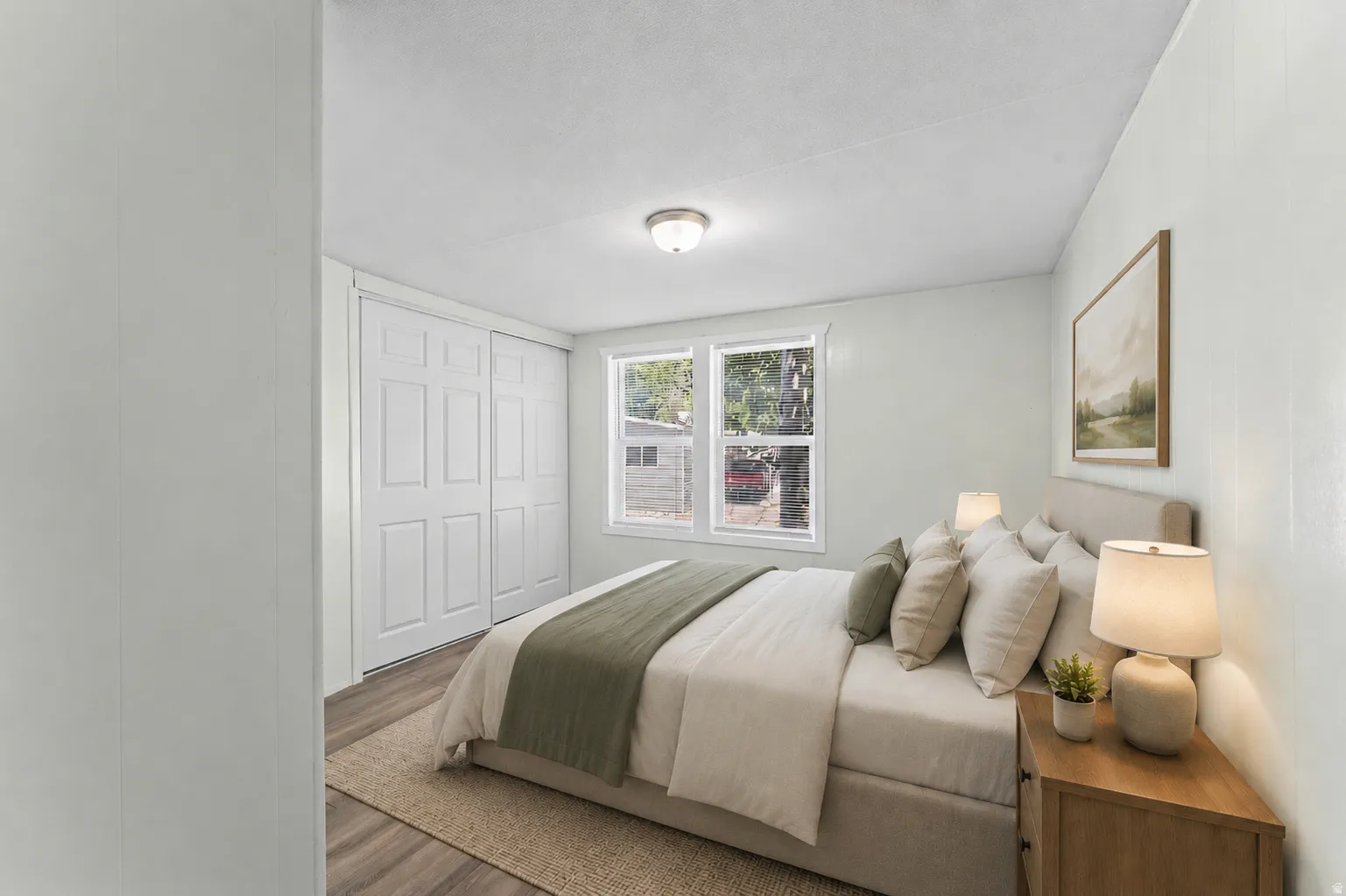 Bedroom featuring light-colored walls, wood-finish flooring, white trim, and a window offering natural illumination