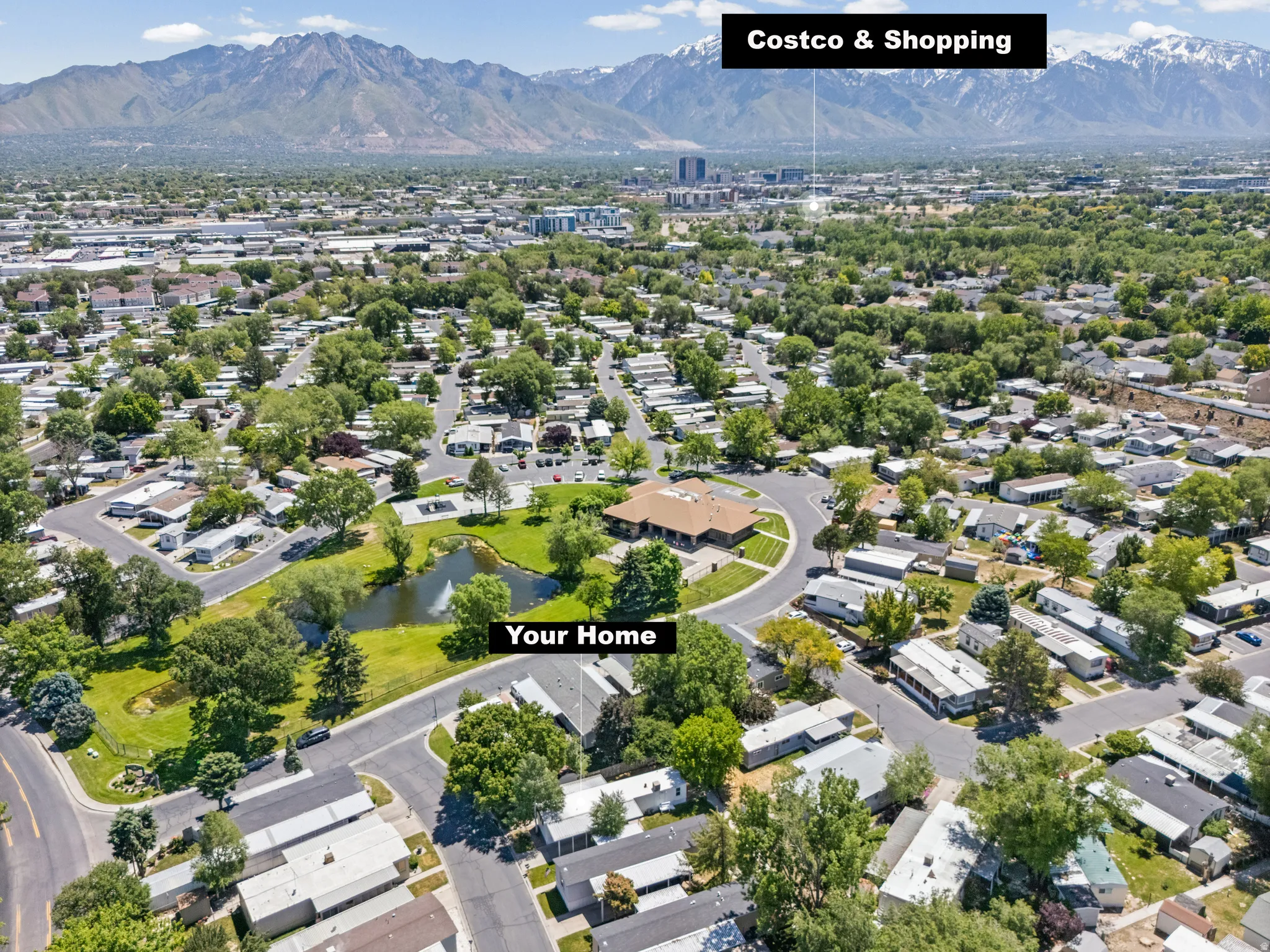Aerial perspective showcasing a residential community with mature trees and a central pond with a fountain