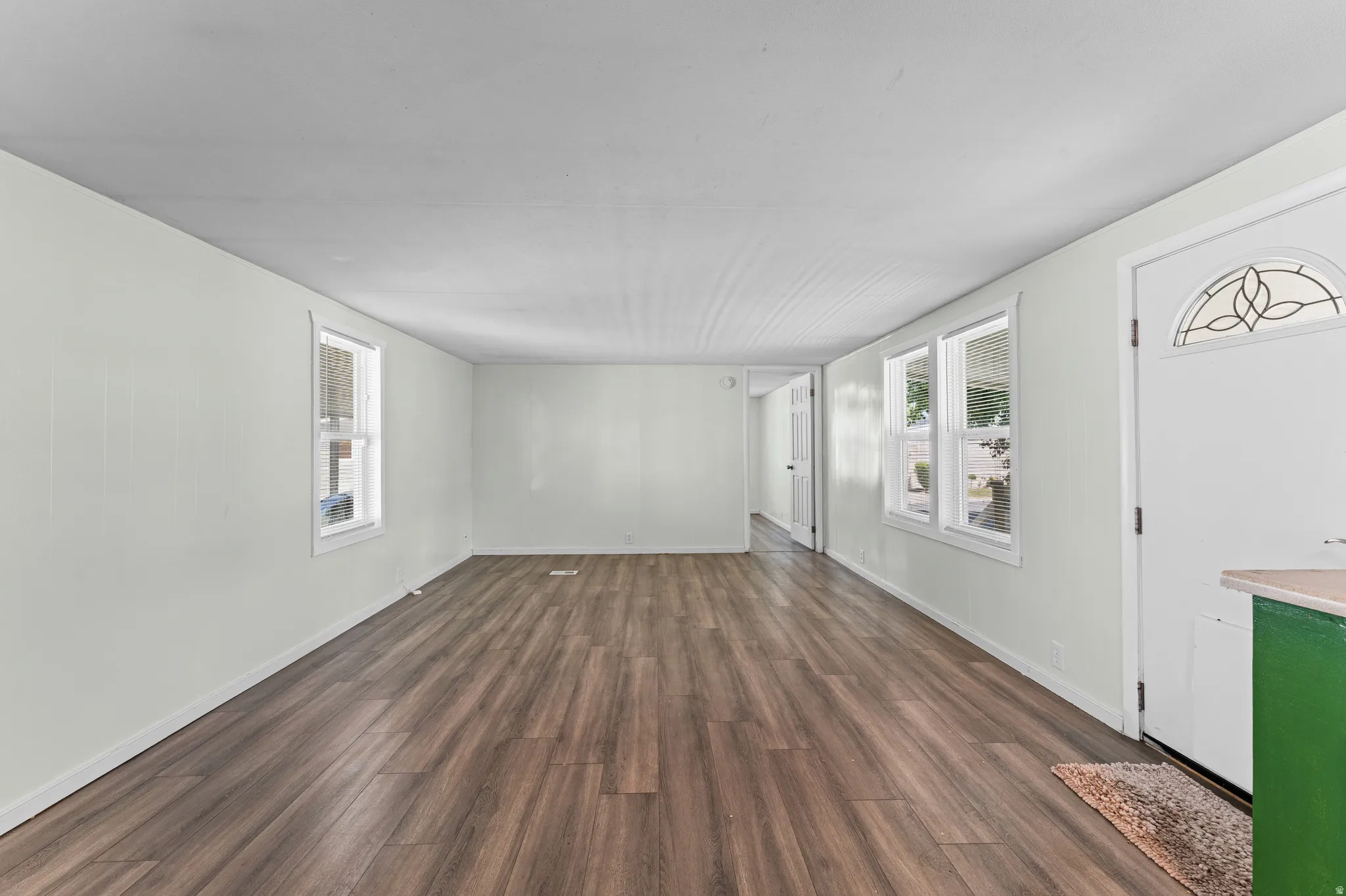 Spacious room featuring wood-finish flooring, light-toned walls, and multiple windows