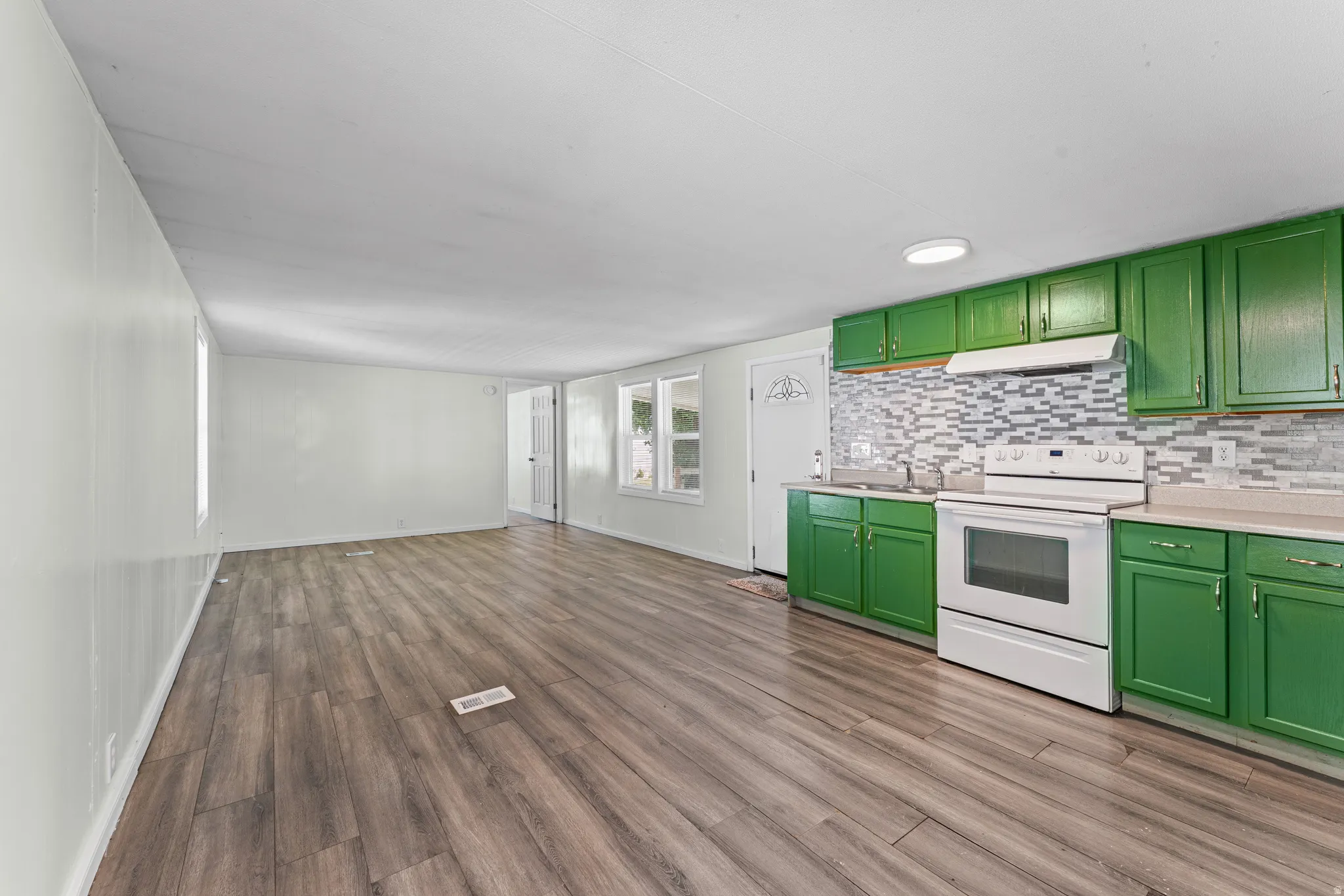 Open-concept room featuring wood-finish flooring, white walls, and a kitchen area