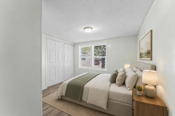 Bedroom featuring light-colored walls, wood-finish flooring, white trim, and a window offering natural illumination