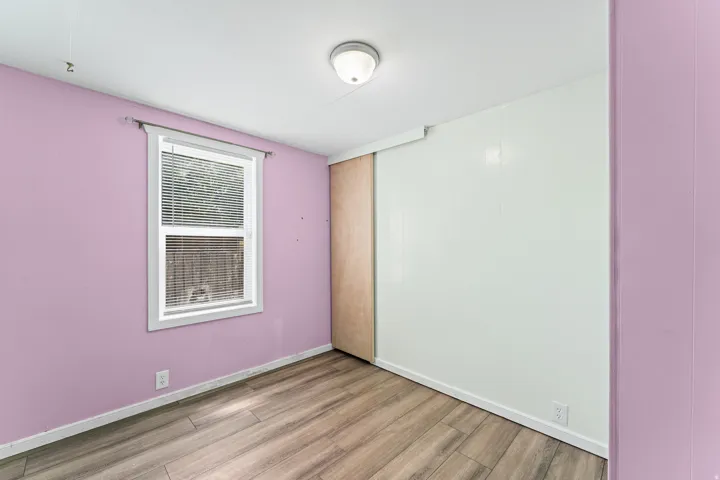 Room featuring wood-finish flooring, a window with horizontal blinds, and a flush mount ceiling light fixture