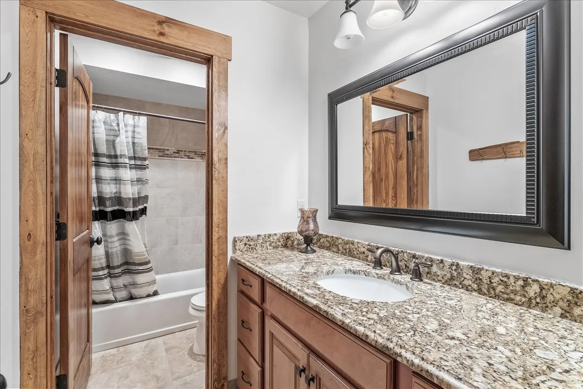 Bathroom vanity featuring a granite countertop, undermount sink, and dark bronze hardware
