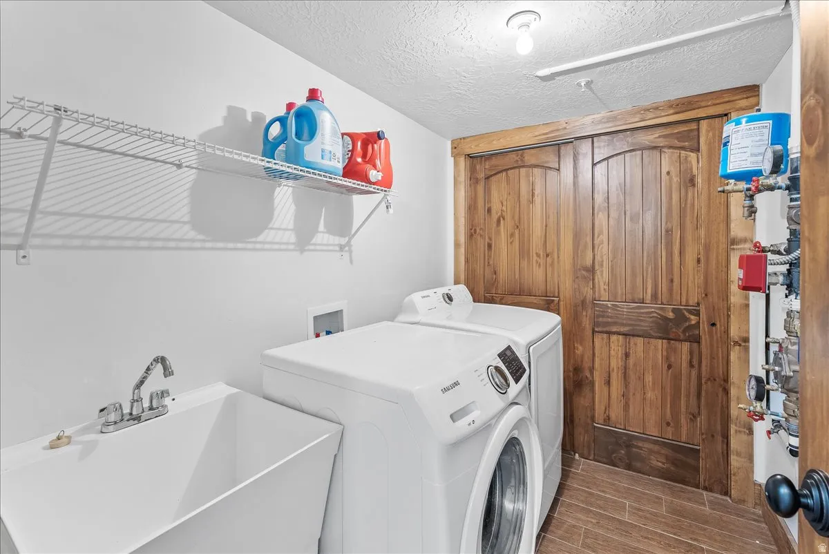 Dedicated laundry area featuring a utility sink, wall-mounted wire shelving, and wood-finish flooring