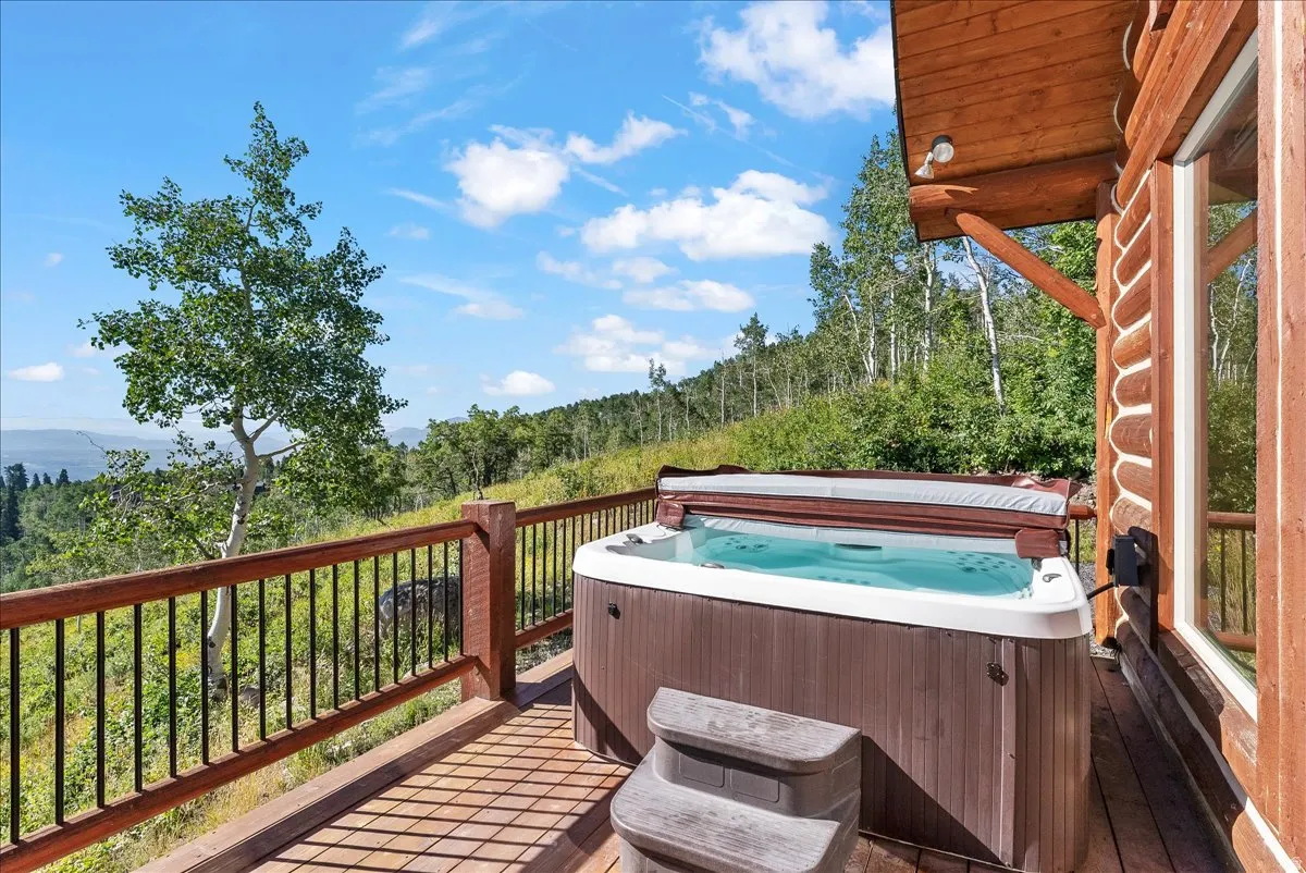 Deck featuring a built-in hot tub with a protective cover, a two-step entry, and wood-finish railings