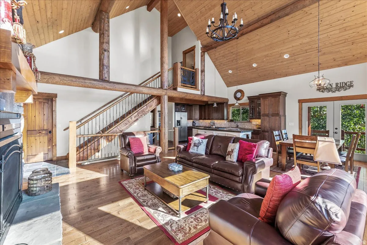 Open concept living area featuring wood-finish flooring, a stone fireplace, and exposed wood beams