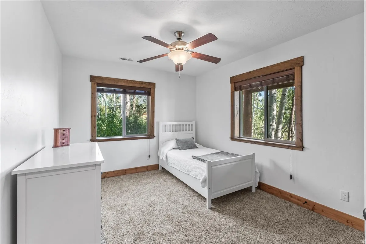 Bedroom featuring white walls, textured carpeting, and wood-trimmed windows