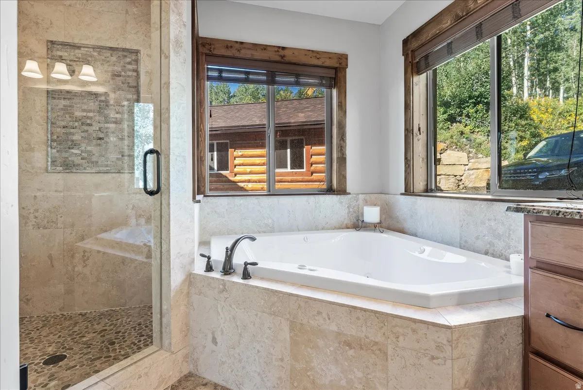 Corner jetted tub set within a tiled surround, featuring a dark-finish faucet