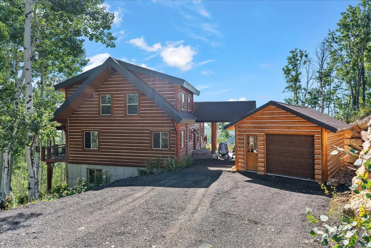 Log-sided residence featuring a covered entry, attached deck, and multi-pane windows