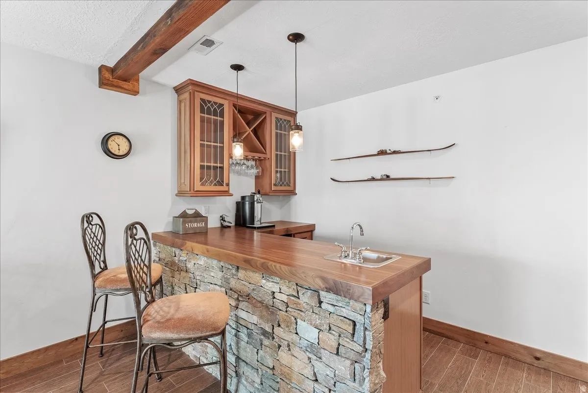 Custom wet bar featuring a stone-clad base, wood-finish countertop, and integrated sink