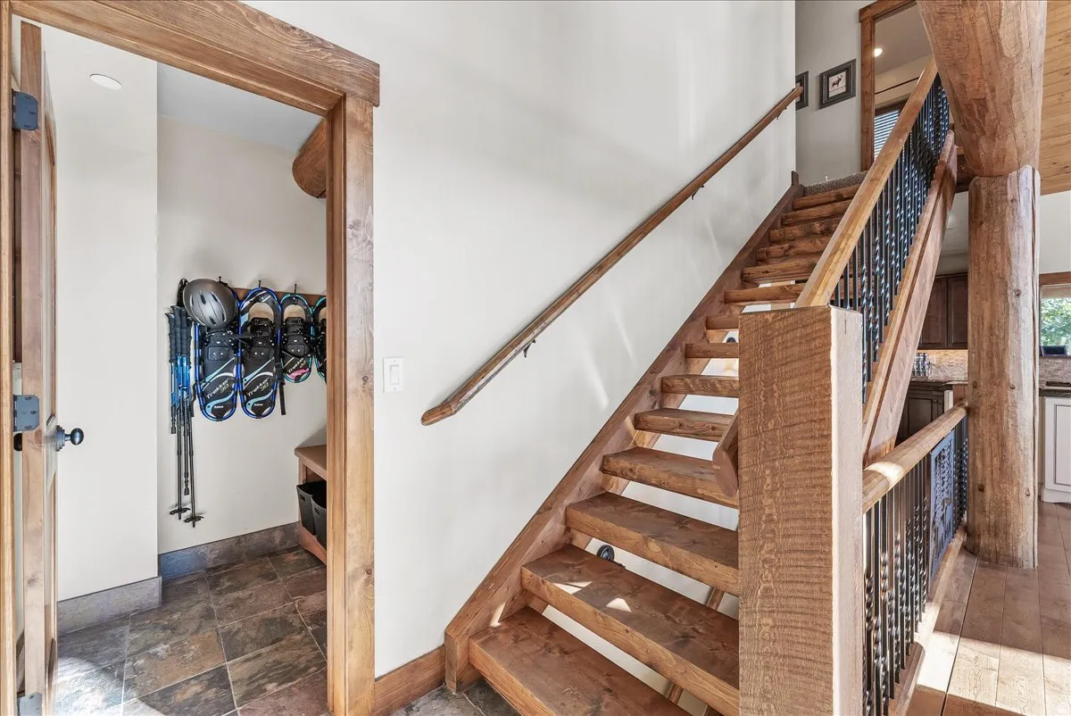 Wood-finish staircase with wrought iron balusters and a prominent wood newel post