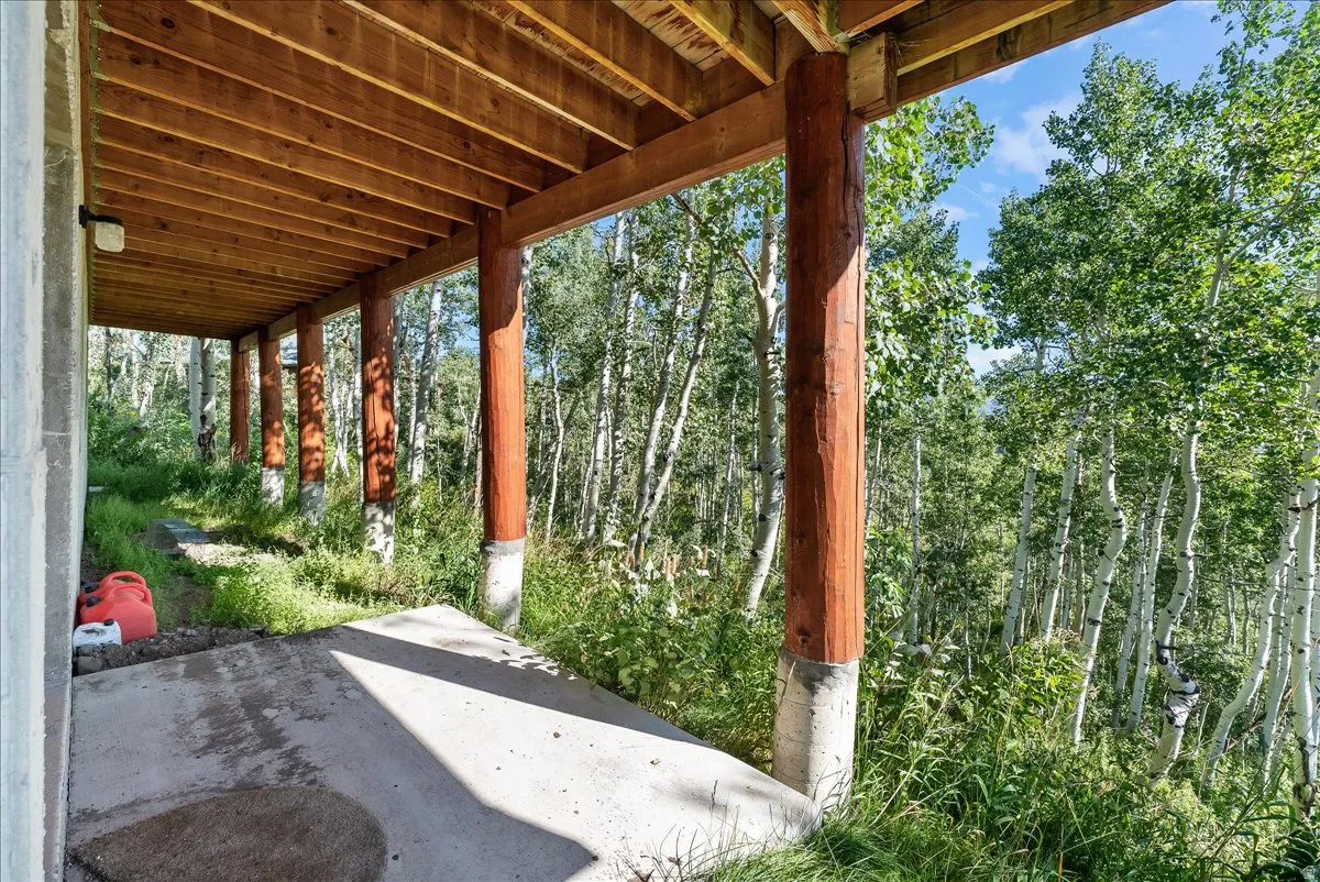 Covered patio featuring a concrete surface, exposed wood ceiling, and log support columns