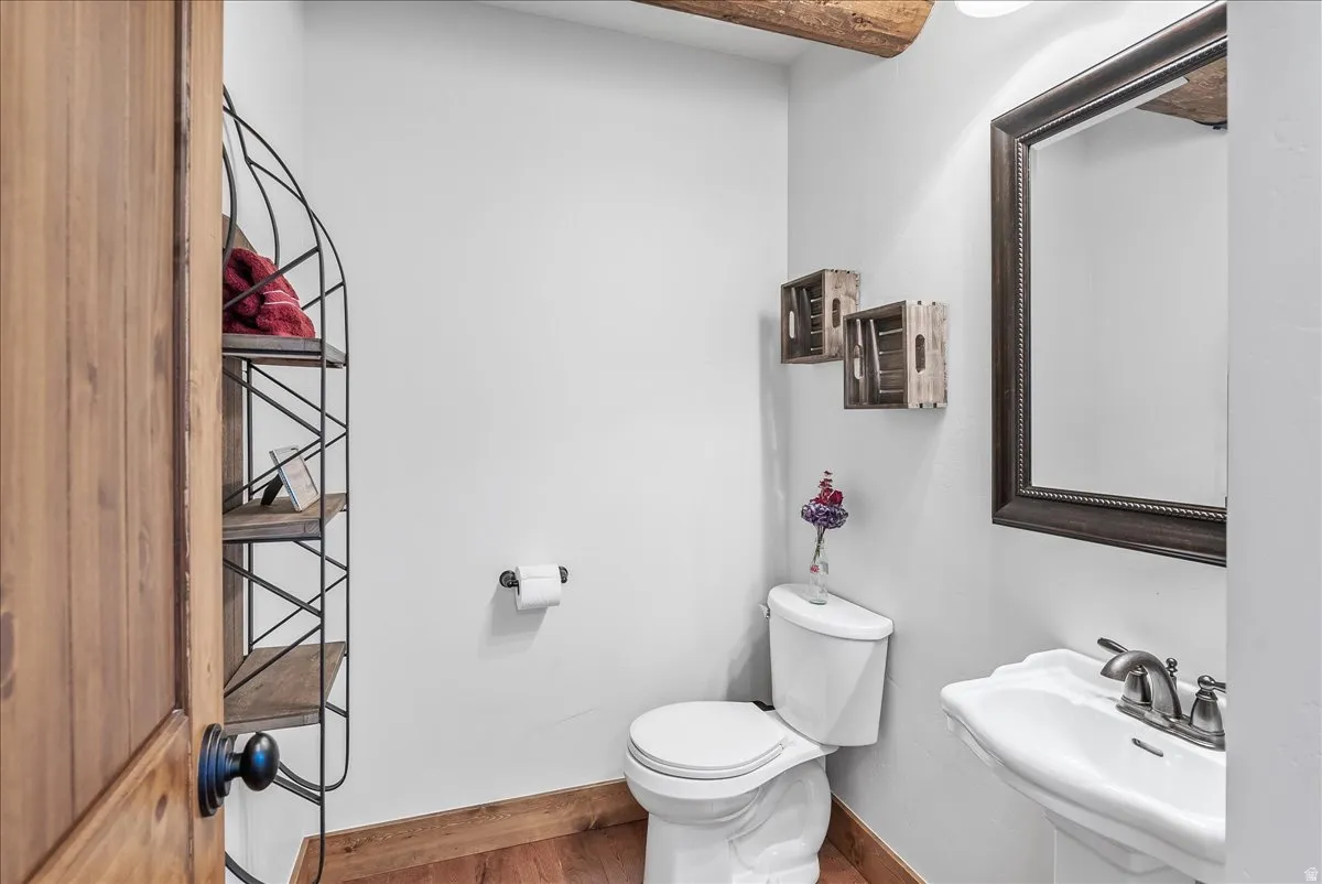 Powder room featuring a pedestal sink with a brushed nickel faucet, a framed mirror, and a toilet
