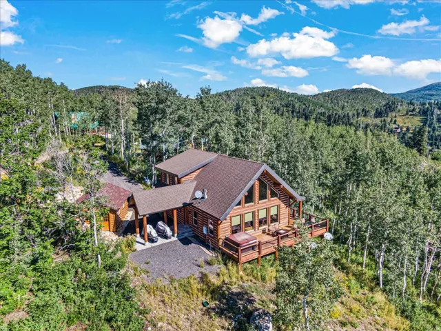 Log-sided residence featuring a multi-level deck, a prominent A-frame window design, and an attached covered carport