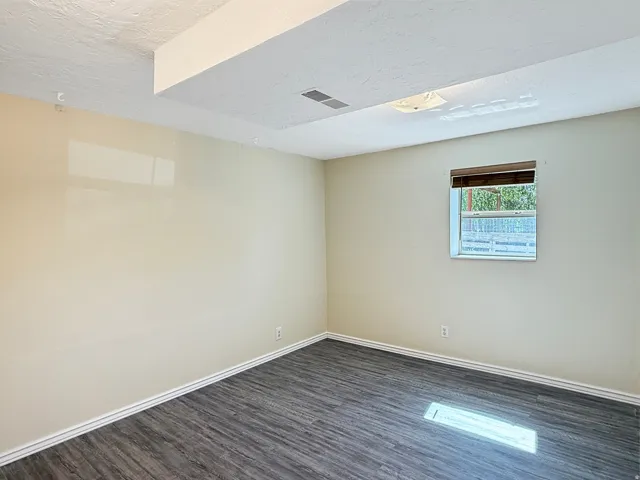 Room featuring wood-finish flooring, neutral wall tones, and white trim