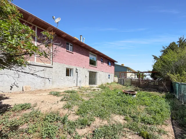 Rear exterior featuring brick siding, a lower-level concrete foundation, and a walk-out patio door
