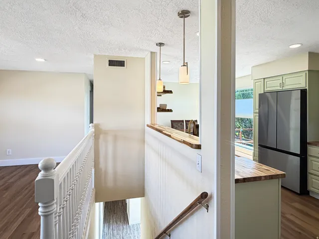 Upper-level landing featuring wood-finish flooring, white spindle railing, and recessed lighting