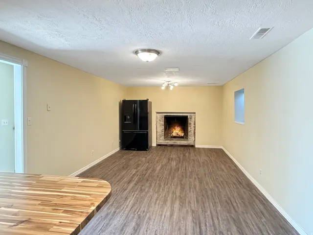 Spacious interior featuring wood-finish flooring, a contemporary fireplace with a stone surround, and an integrated black refrigerator