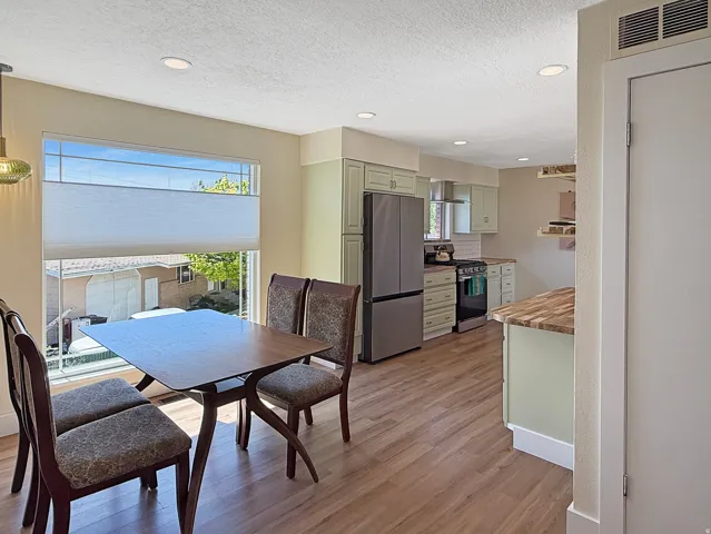 Open-concept living space featuring wood-finish flooring, recessed lighting, and a prominent window