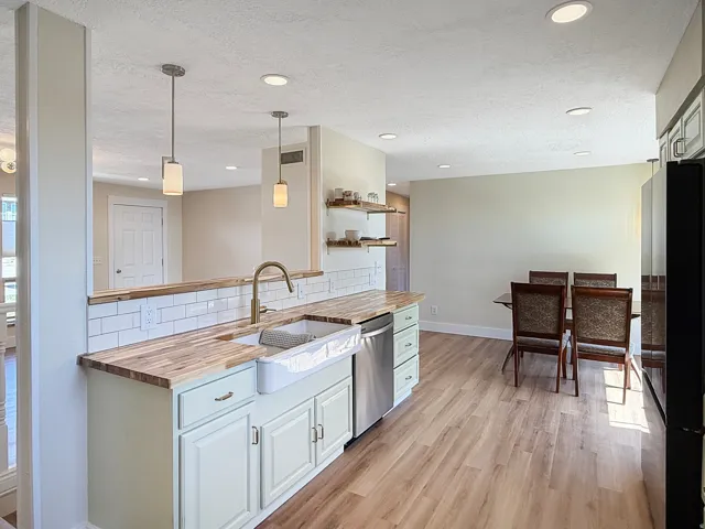 Kitchen with light wood-finish flooring, white subway tile backsplash, and light-toned cabinetry
