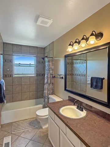 Full bathroom featuring a single vanity with a laminate countertop, a framed mirror, and a five-light vanity fixture