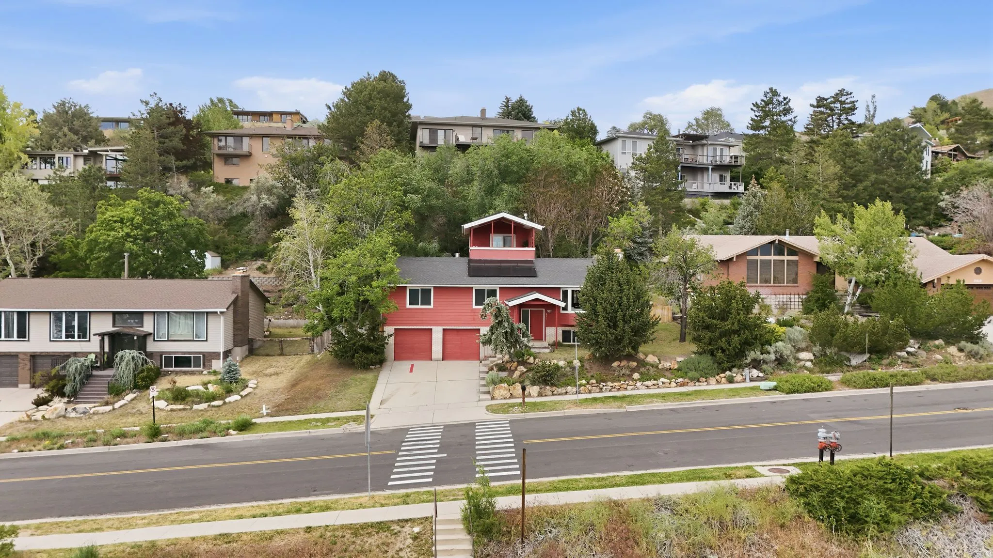 Red exterior with a distinct cupola feature, two-car garage, and an elongated driveway