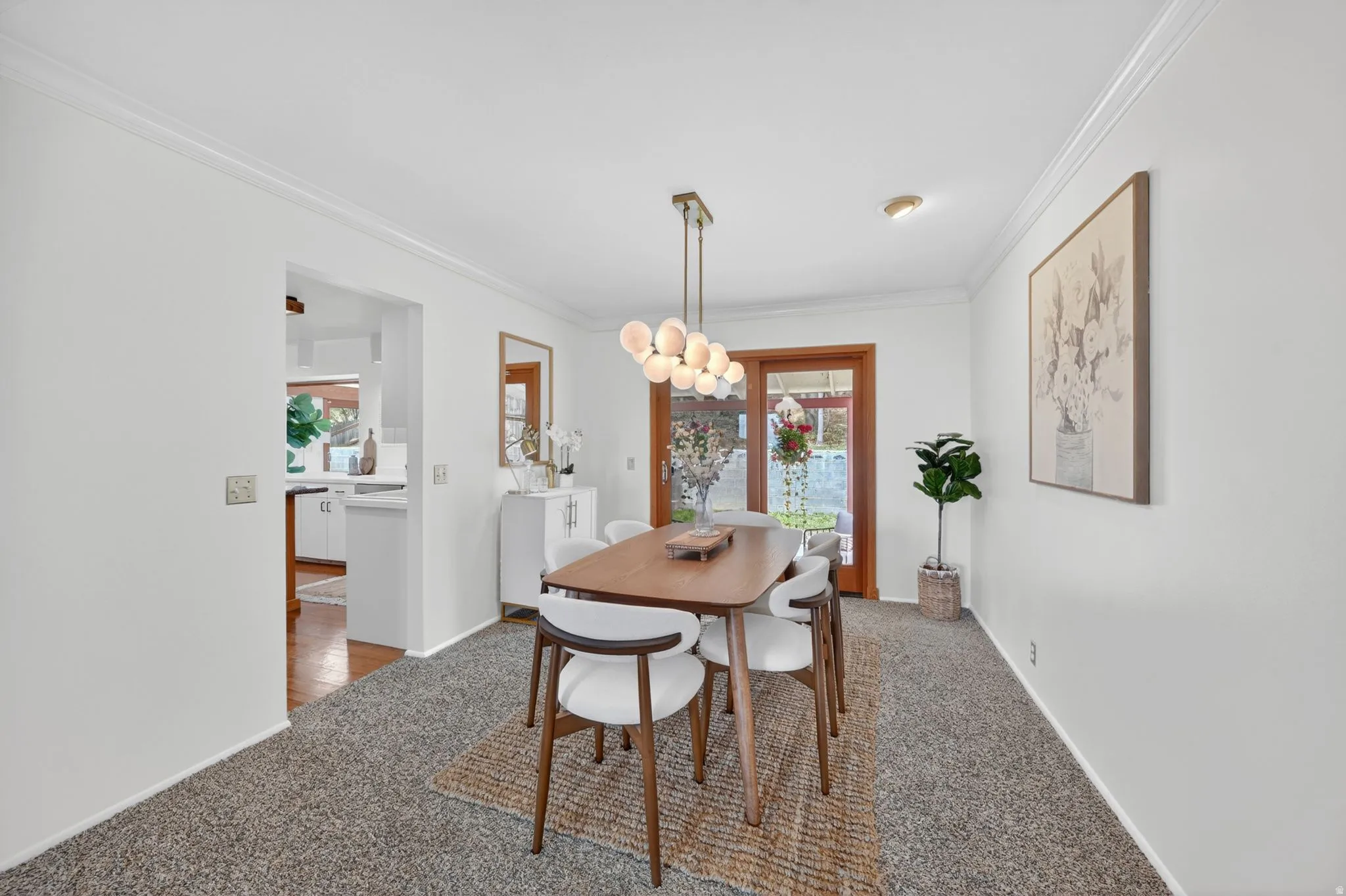 Dining area featuring a modern chandelier, light-colored walls, and crown molding