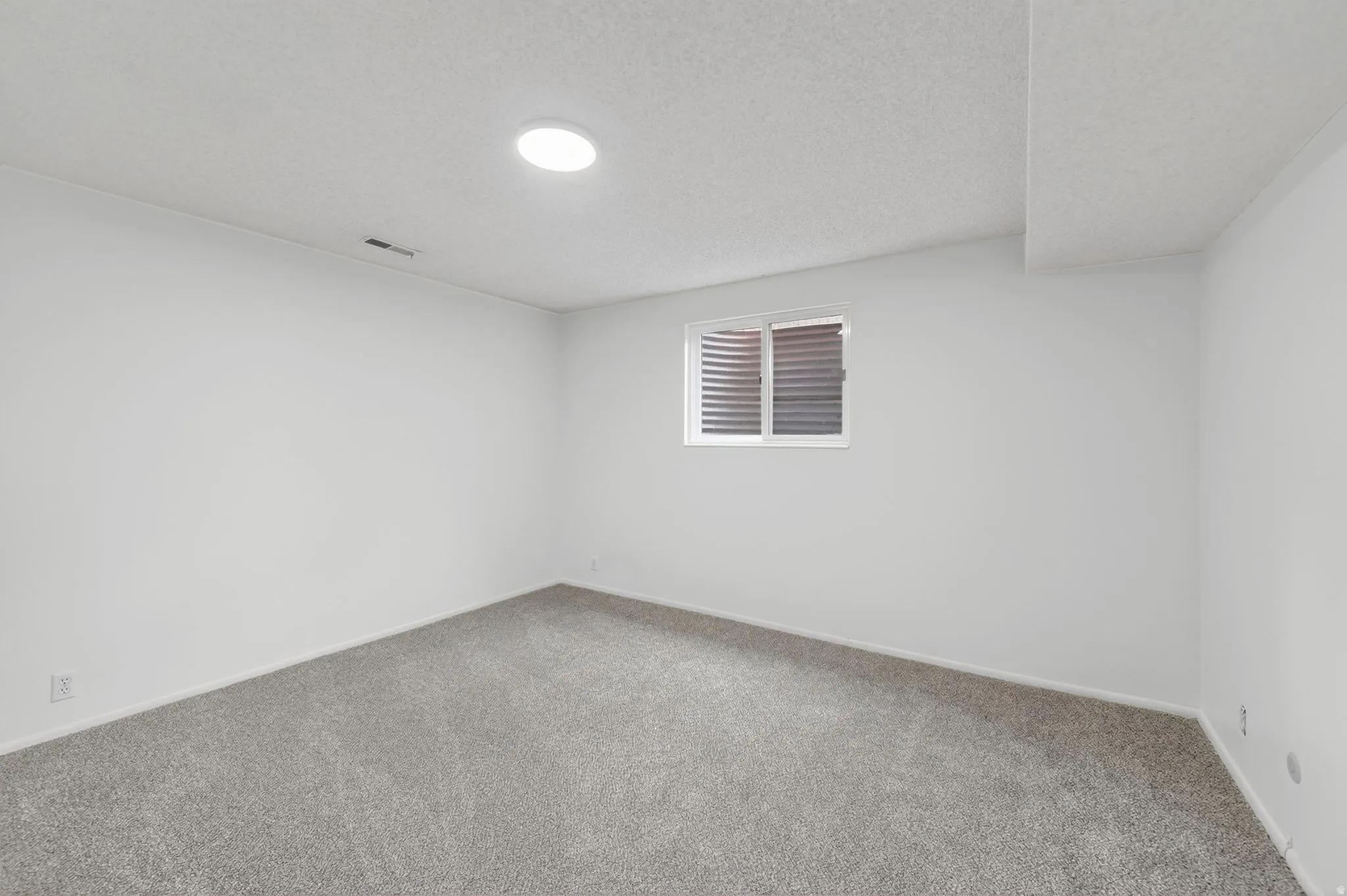 Large bedroom downstairs with fresh paint, lighting and carpet.