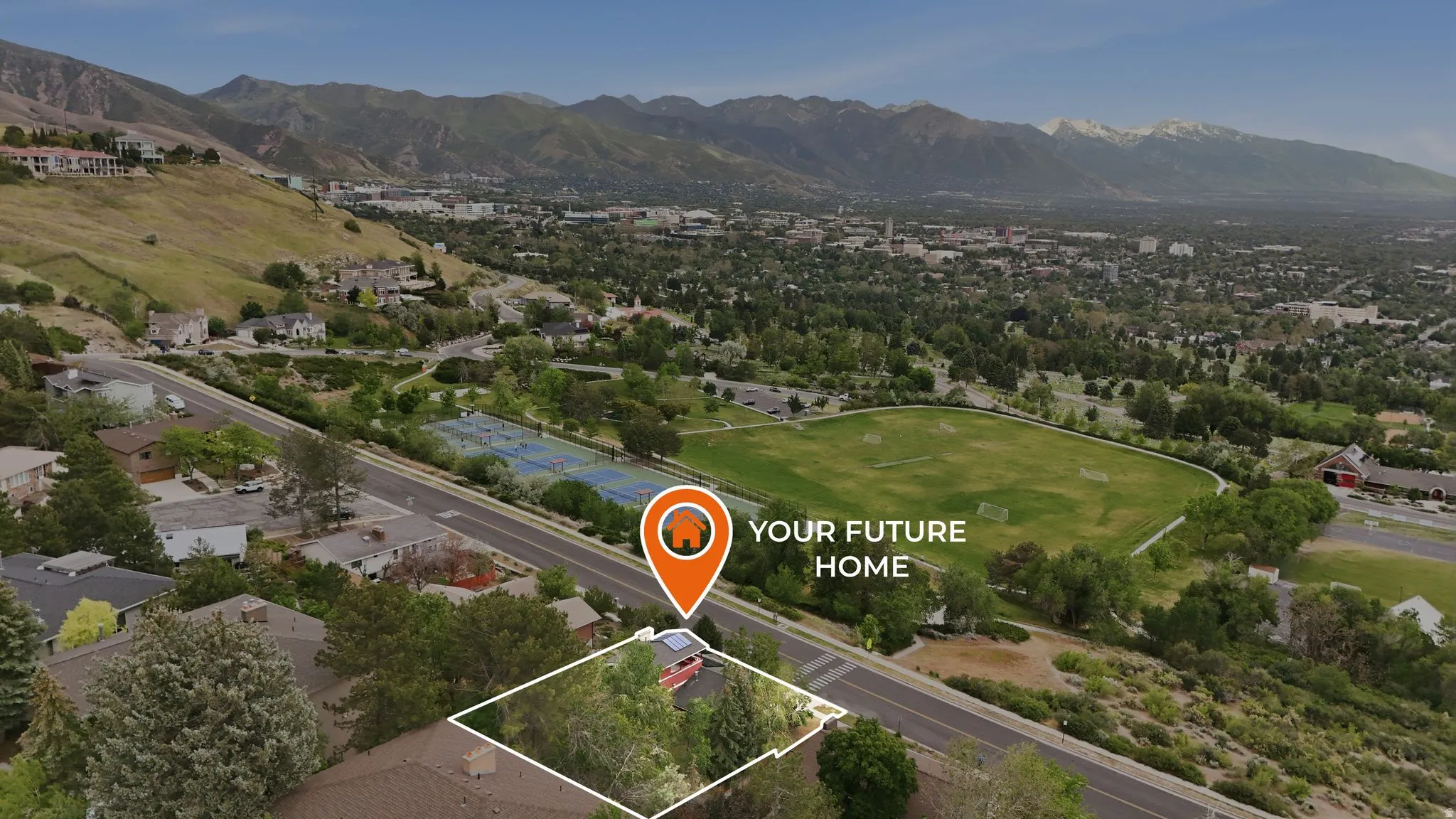 Expansive parcel featuring mature trees, a paved road, and a backdrop of mountainous terrain