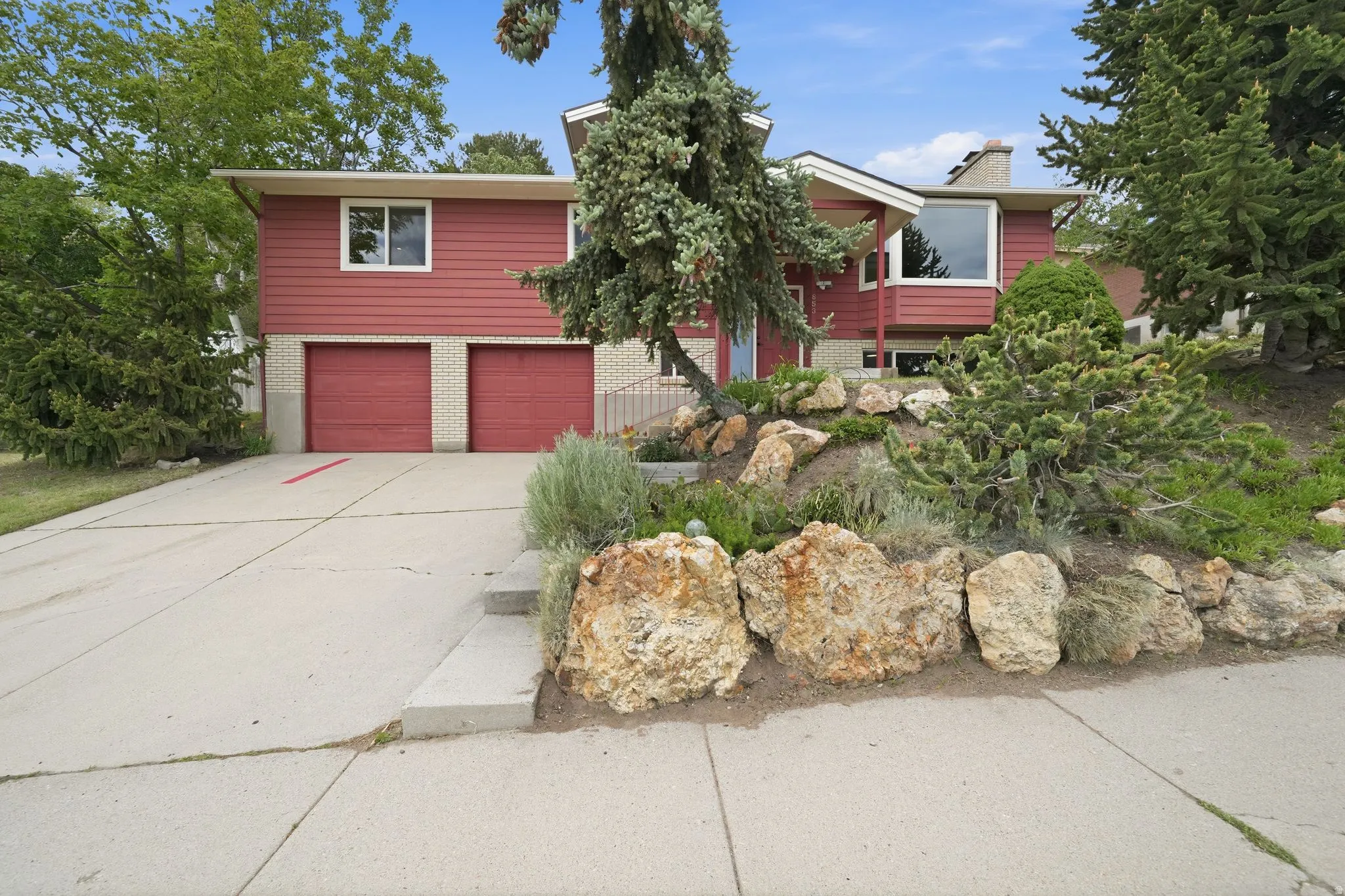 Split-level residence featuring a red siding exterior and a two-car garage with red doors