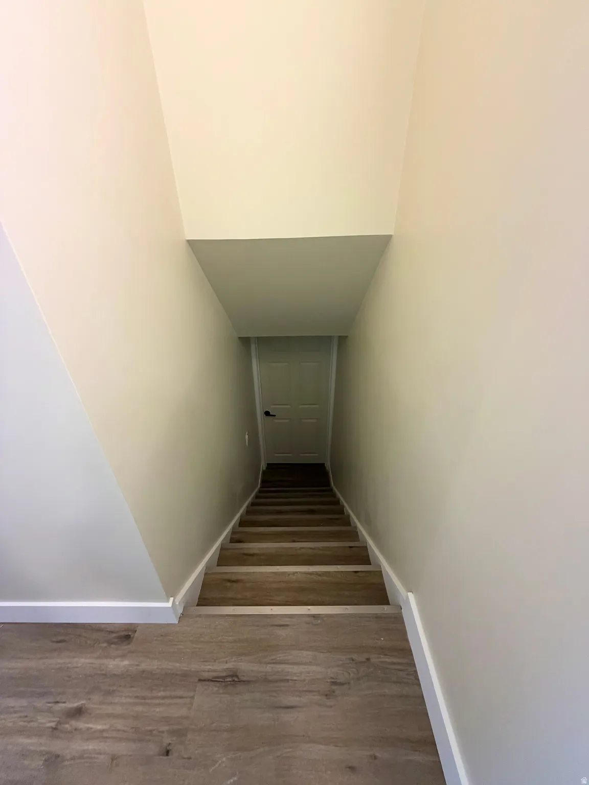 Staircase featuring wood-finish treads and risers, white baseboards, and neutral wall paint