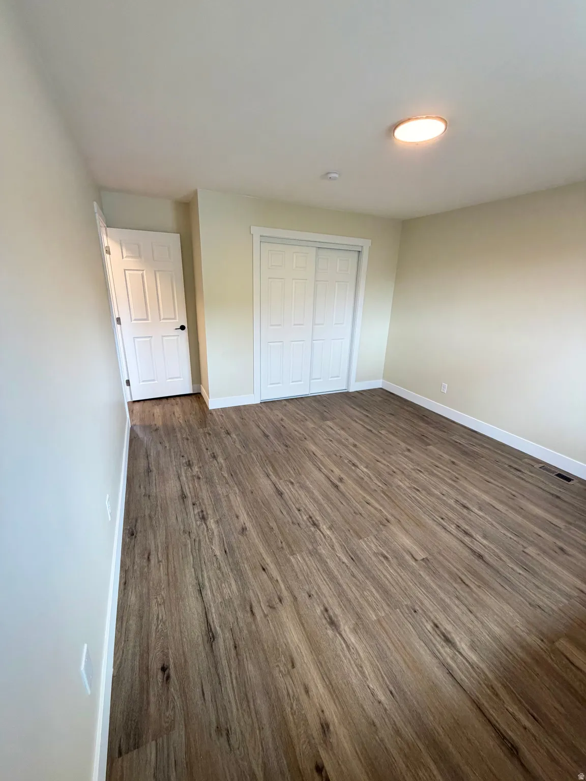 Room featuring wood-finish flooring, light neutral wall paint, and white trim