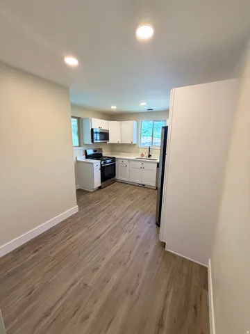 Modern kitchen featuring white cabinetry, stainless steel appliances, and wood-finish flooring