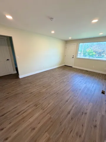 Spacious room featuring wood-finish flooring, recessed lighting, and light-toned walls
