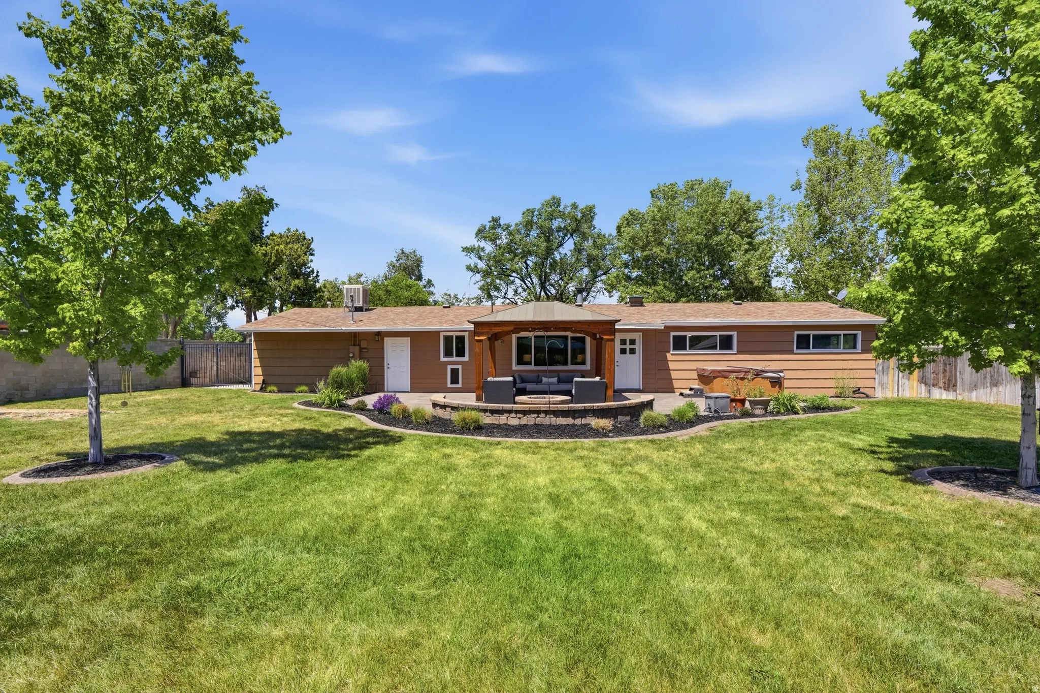 Spacious backyard featuring a large lawn, mature trees, and a stone-paver patio