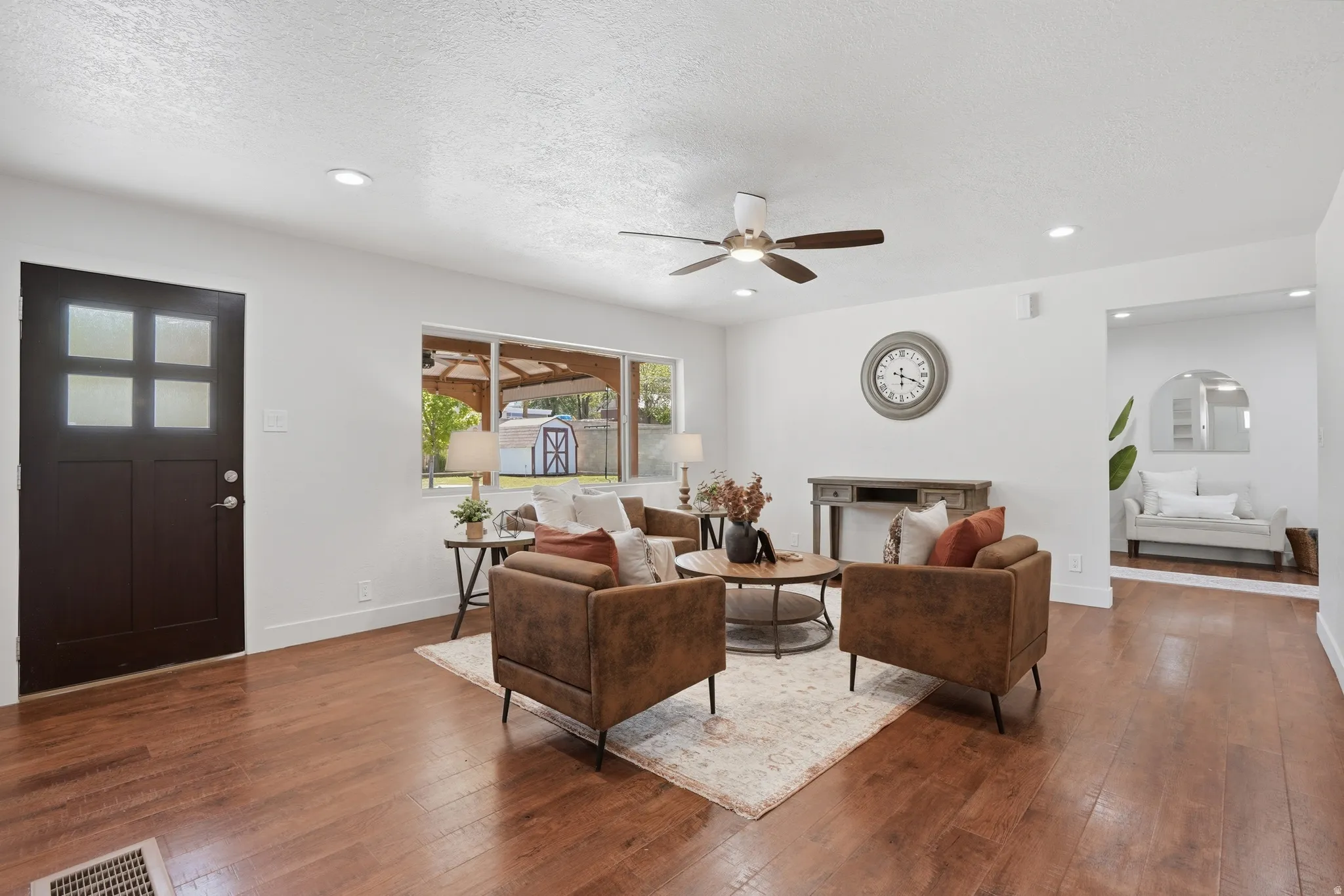 Spacious living area featuring wood-finish flooring, a ceiling fan, recessed lighting, and a large picture window