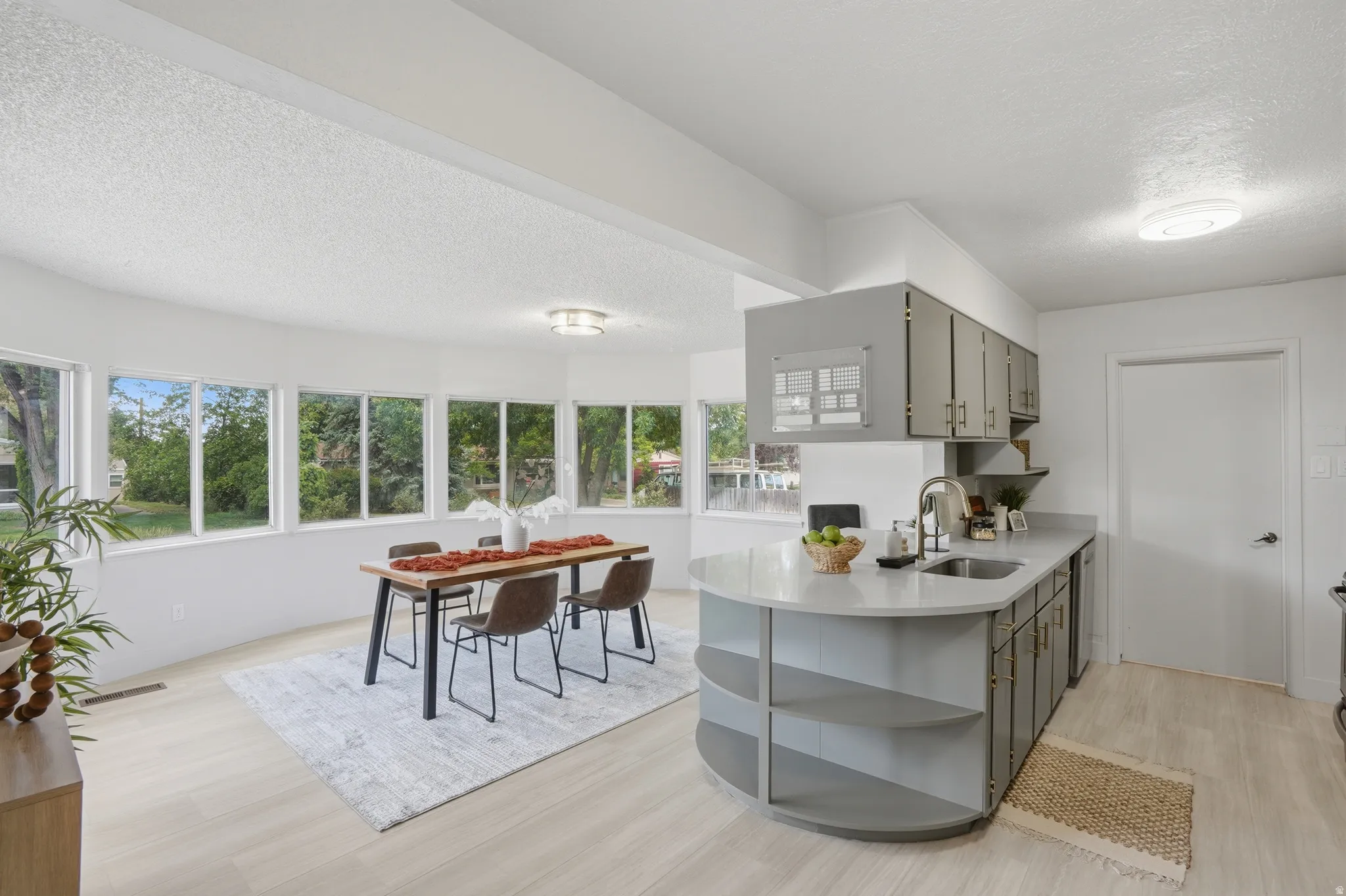 Open-concept living space with LVP Tile flooring, bay of windows, and a kitchen island with integrated shelving