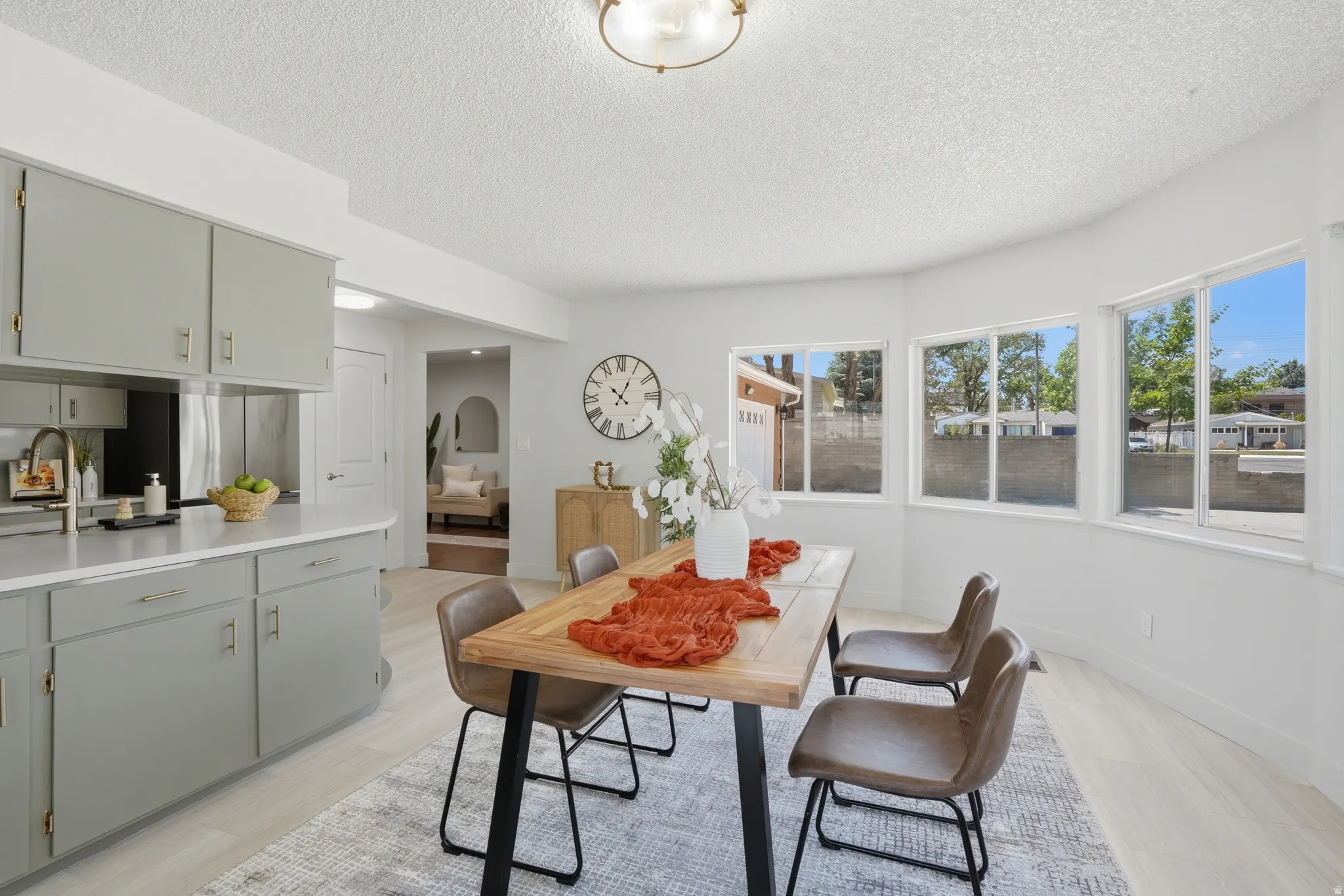 Bright dining area with large bay windows, light LVP Tile flooring, and a modern ceiling fixture