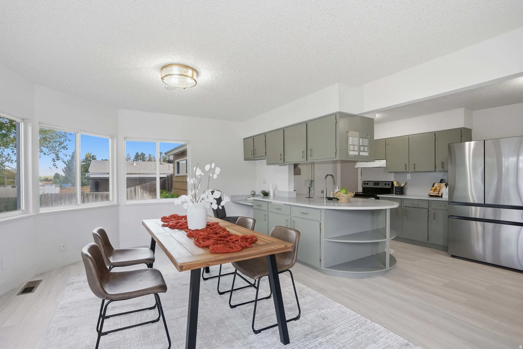 Bright dining area with large bay windows, light LVP Tile flooring, and a modern ceiling fixture