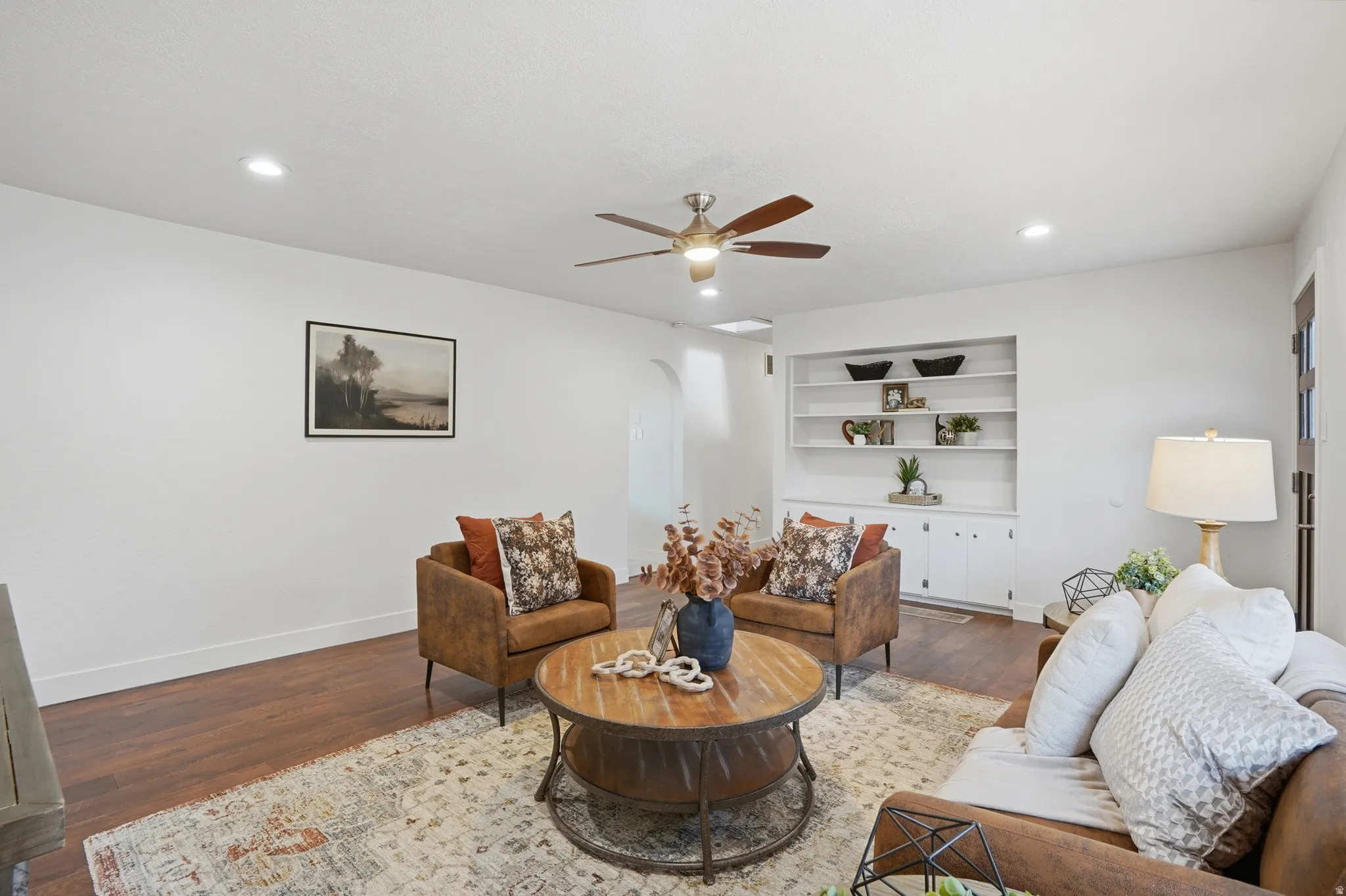 Living area featuring wood-finish flooring, recessed lighting, built-in shelving, a ceiling fan.