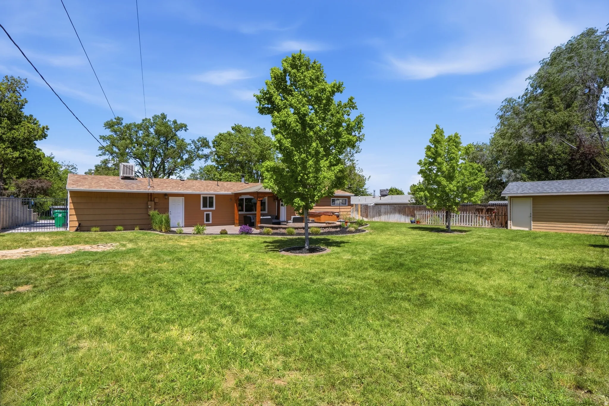 Expansive lawn area with mature trees and a detached shed